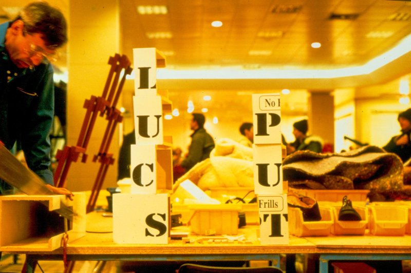 Image: An operative on the factory line saws a wooden box into pieces which he neatly arranges into stacks, one of which spells 'put', during Break Down, 2001. Photograph: Parisa Taghizadeh
