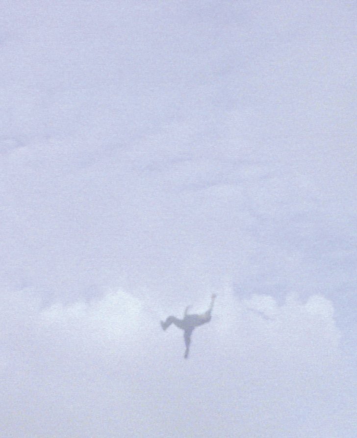 Still from Steve McQueen's Caribs' Leap, 2002 depicting a figure mid-flight against a cloudy sky.