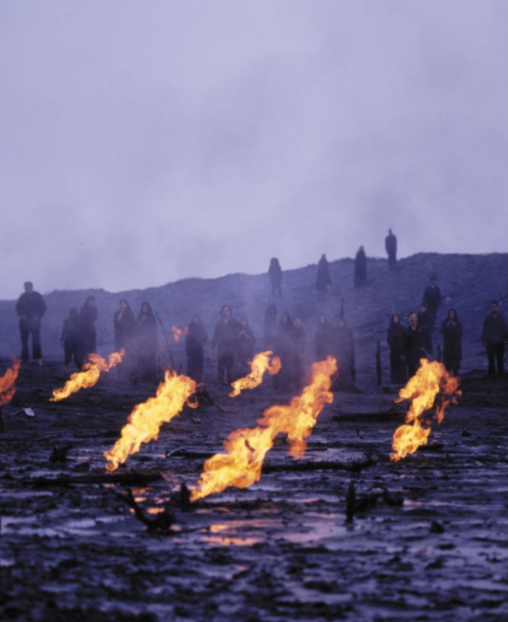 Image: Still from the film that formed part of the performance at The Union Chapel, featuring Sussan Deyhim and a choir, emerge from the charred horizon, obscured by smoke and flames in the foreground. Still: Shoja Azari, Sussan Deyhim, Ghasem Ebrahimian and Shirin Neshat