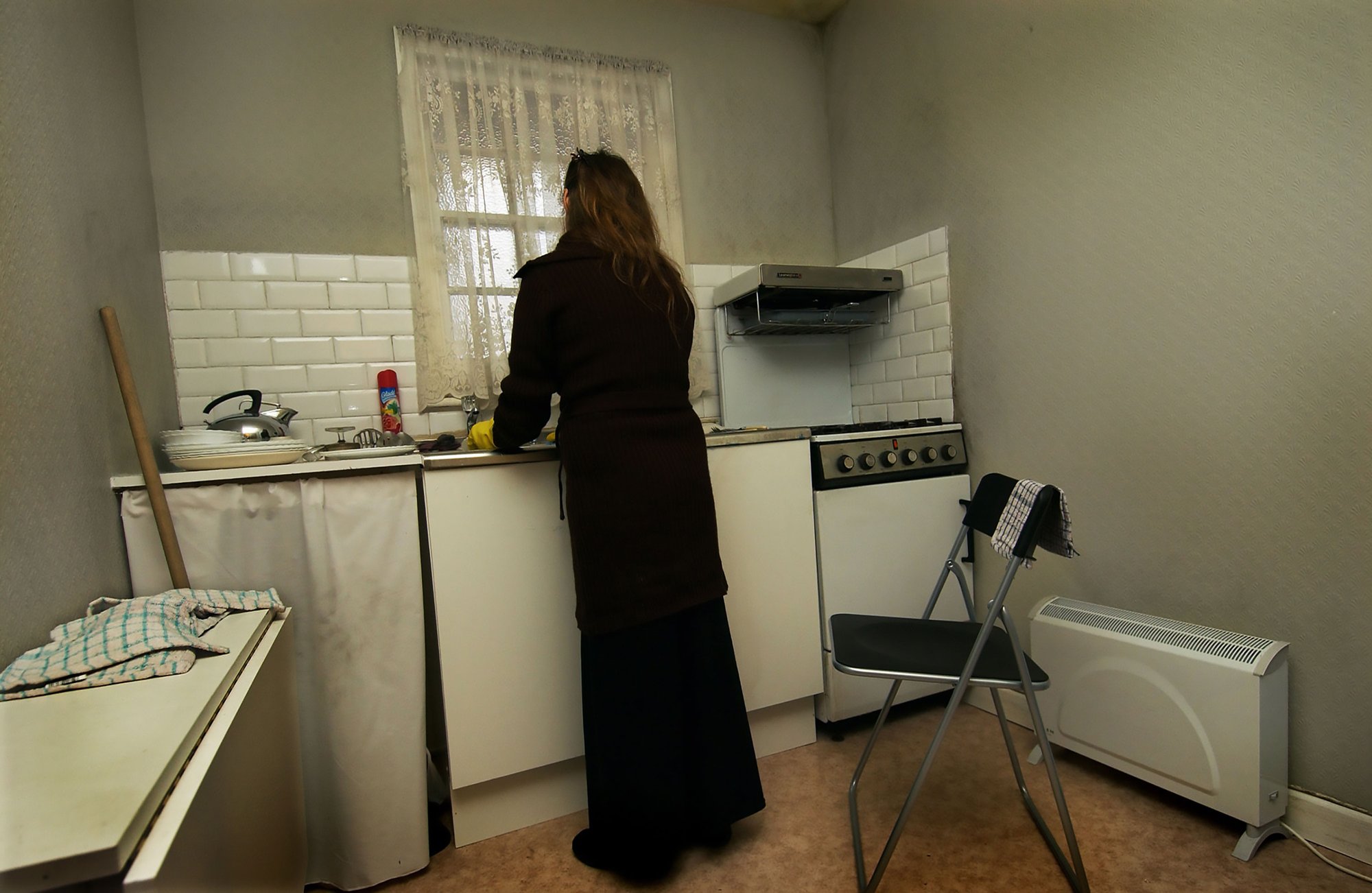 A woman washes dishes in the kitchen sink at Walden Street, Die Familie Schneider, 2004.