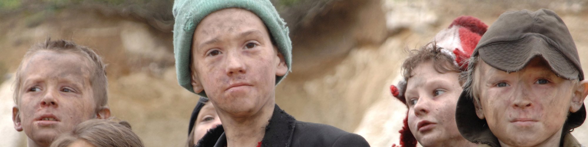 A group of young children with smudges on their faces and dirty clothes look at the camera. Film still from Exodus dir. Penny Woolcock, Margate 2006