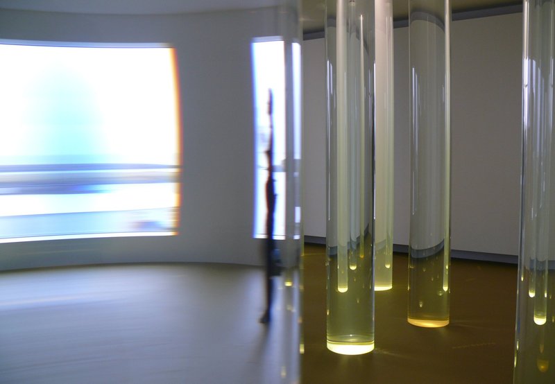 Glass columns of water in a room, with half the room distorted through a column