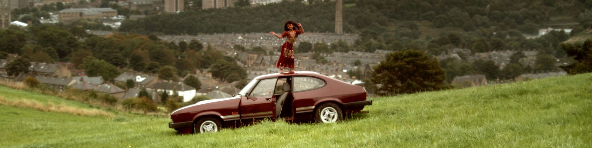 Video still from The Arbor: Young Lorraine (Parvani Lingiah) dancing on the roof of her father’s car.