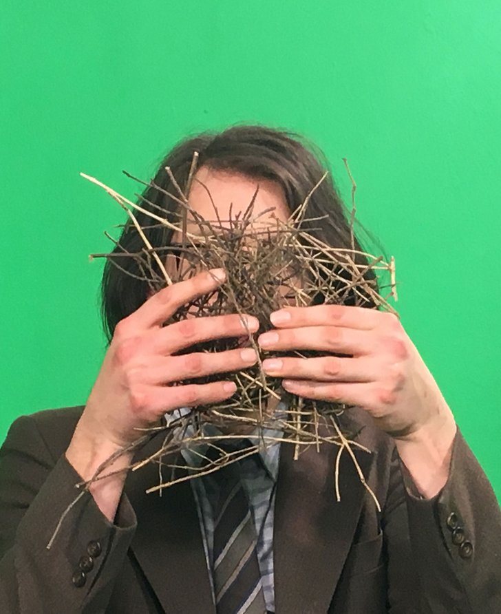 Andy Holden holding a nest obstructing his face in front of a green screen during production of Andy Holden & Peter Holden: Natural Selection, 2017. Photograph: Jazbo Gross
