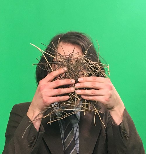 Andy Holden holding a nest obstructing his face in front of a green screen during production of Andy Holden & Peter Holden: Natural Selection, 2017. Photograph: Jazbo Gross