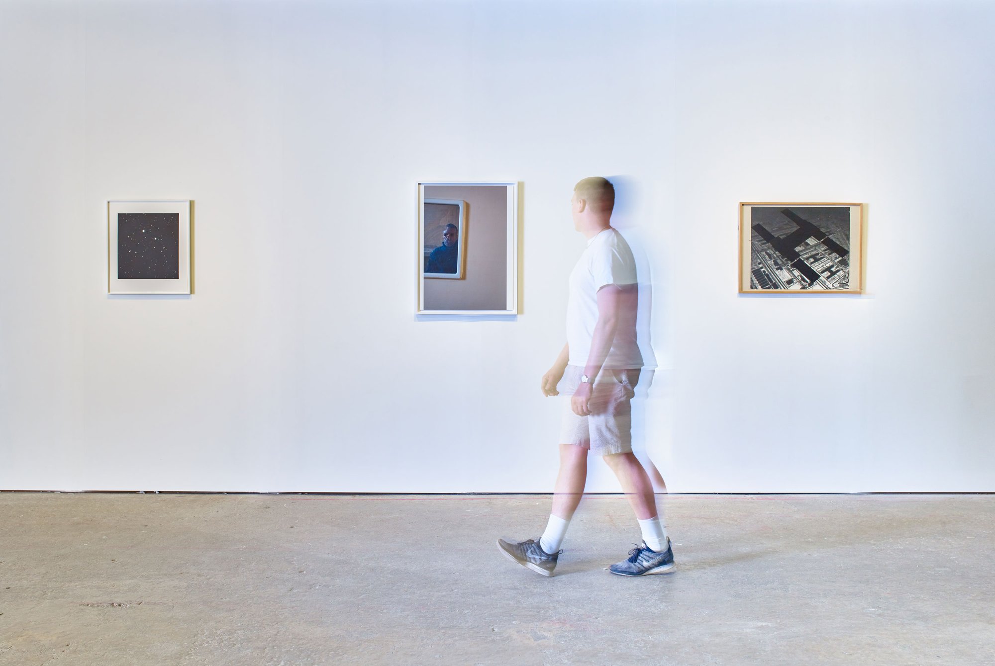 Exhibition visitor walking in front of Vija Celmins' mezzotint work Untitled #4, 2016, Wolfgang Tillmans' self-portrait Separate System, Reading Prison (self a), 2016; and Rita Donagh's photographic print Single Cell Block, 1984. Photograph: Stephen White.