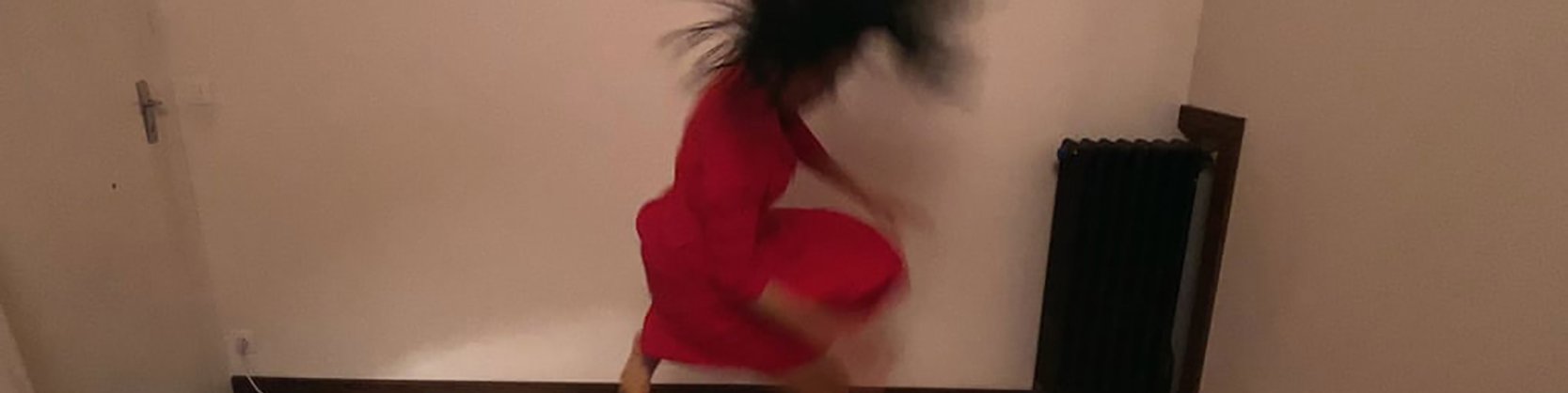 Person in red outfit in motion, with dark hair flipping and blurred