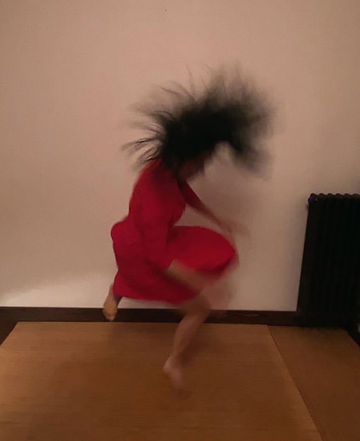 Person in red outfit in motion, with dark hair flipping and blurred