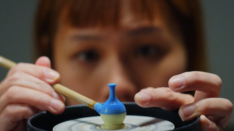 Film still: close up of a person spinning a miniature vase on a pottery wheel.